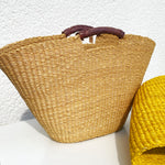 Handwoven Bolga basket bag made from elephant grass with leather handle, crafted in Ghana