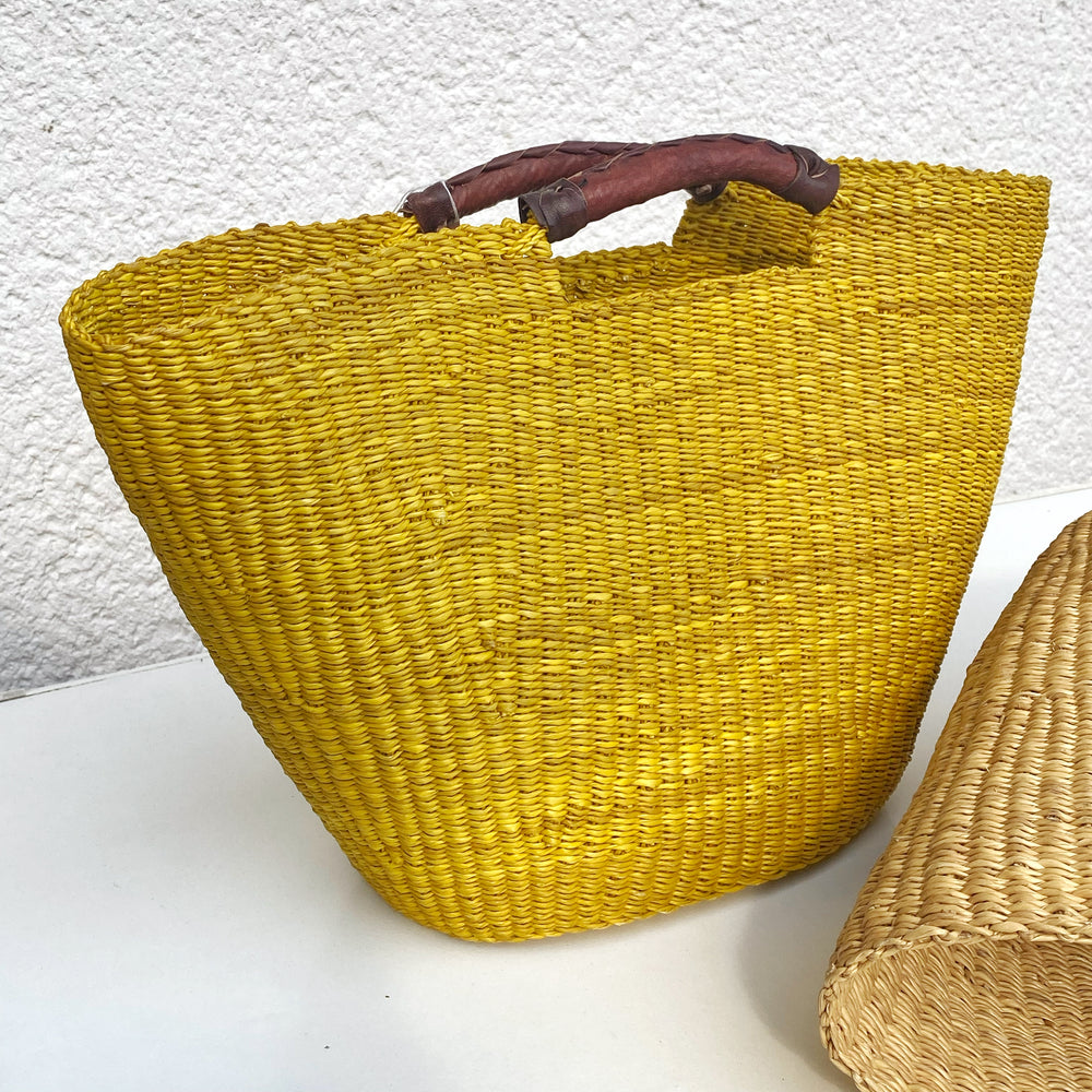 Handwoven Bolga basket bag made from elephant grass with leather handle, crafted in Ghana