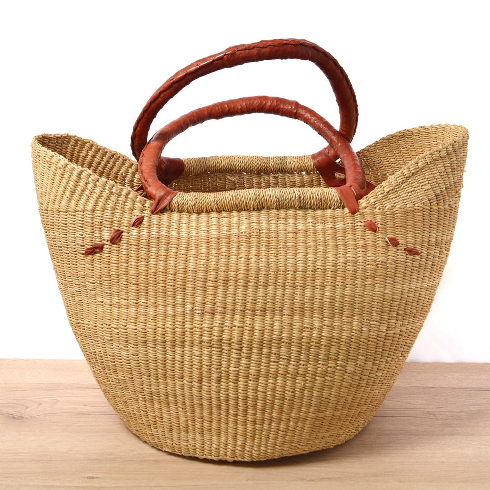 Woven basket with leather handles on a wooden surface