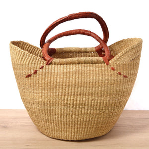 
                  
                    Woven basket with leather handles on a wooden surface
                  
                