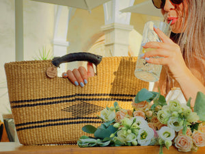 
                  
                    A woman seated at a table, casually holding a straw bag beside her, sipping lemonade and enjoying a moment of relaxation.
                  
                