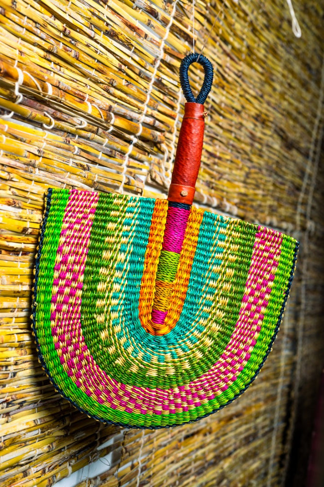 colorful bolga fan with leather handle on a bamboo blinds