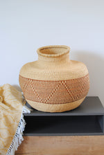 a large vase straw basket in natural colors on a table