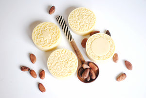 
                  
                    cooca butter lotion bars with cocoa beans on a spoon
                  
                